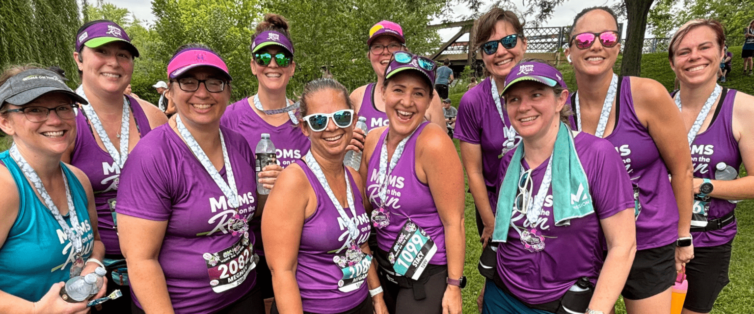 women runners in purple tanks smiling with medals